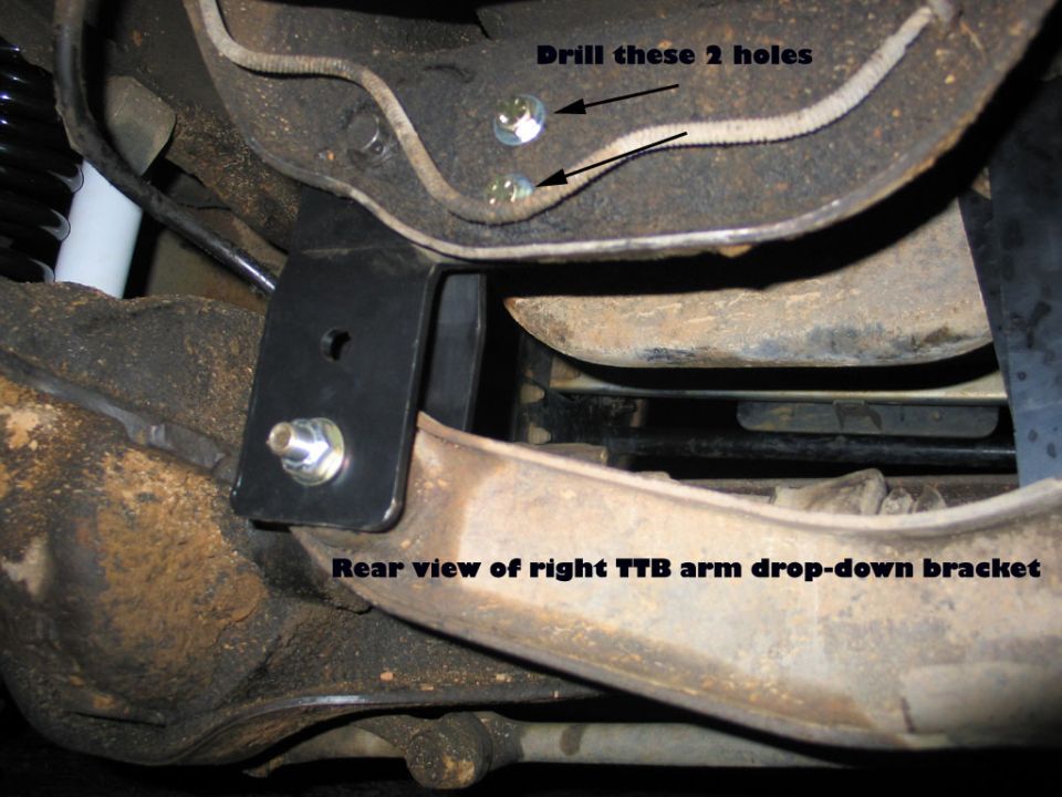 Annotated underbody photo of right TTB drop-down bracket with drill-here arrows