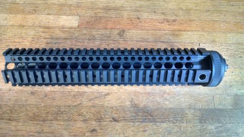 1996 Ford Bronco - A black AR-15 handguard with multiple accessory mounting slots is shown on a wooden background.