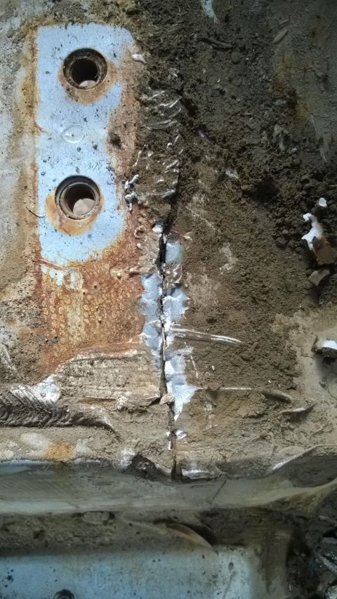 1994 Ford Bronco - Close-up view of a cracked metal frame, showing rust and two bolt holes.