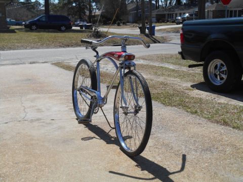 1994 Ford Bronco - A red and chrome cruiser bicycle is parked on a concrete driveway, with a black pickup truck visible to the right.
