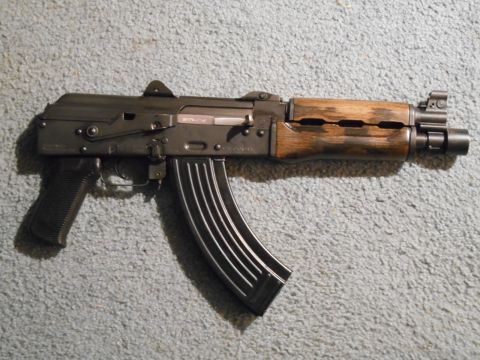 1994 Ford Bronco - This firearm, resembling an AK-47, features a wooden handguard and a curved magazine, resting on a carpeted surface.