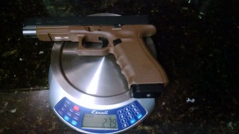 1996 Ford Bronco - A tan pistol is weighed on a digital scale, displaying a weight of 279.