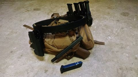 1996 Ford Bronco - A pistol and tactical gear are laid out on a concrete surface, ready for use.