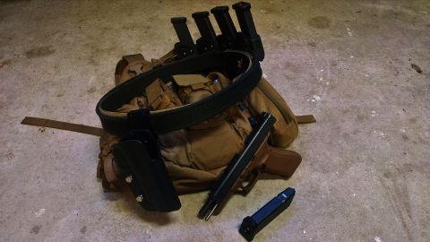 1996 Ford Bronco - Tactical gear, including a backpack, belt, holsters, magazines, and a handgun, is laid out on a concrete surface.