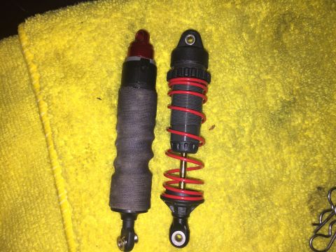 2014 Dodge 1500 - Comparison of two shock absorbers, one with a protective sleeve and the other with a red spring.