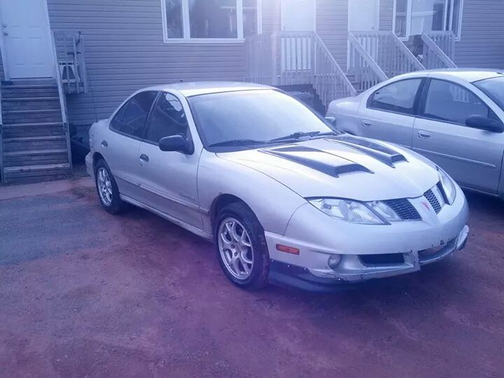 Silver Pontiac Sunfire with hood scoops parked next to another car