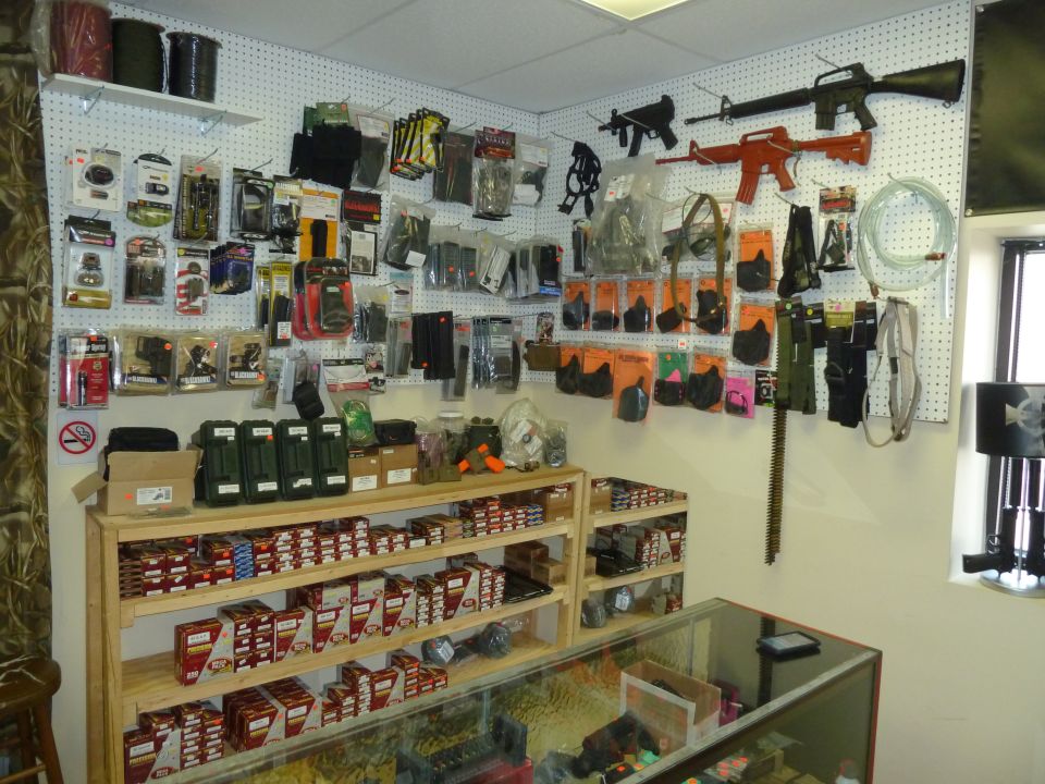 Gun store interior with firearms and accessories on pegboard walls and shelves