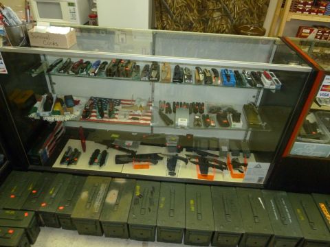 1992 Ford Mustang - A store display case showcases various knives and accessories, with a row of green ammo cans beneath.