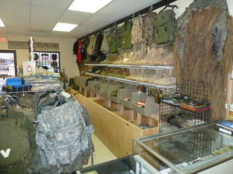1992 Ford Mustang - A store interior displays military gear, including backpacks, vests, boots, and camouflage clothing on racks and shelves.