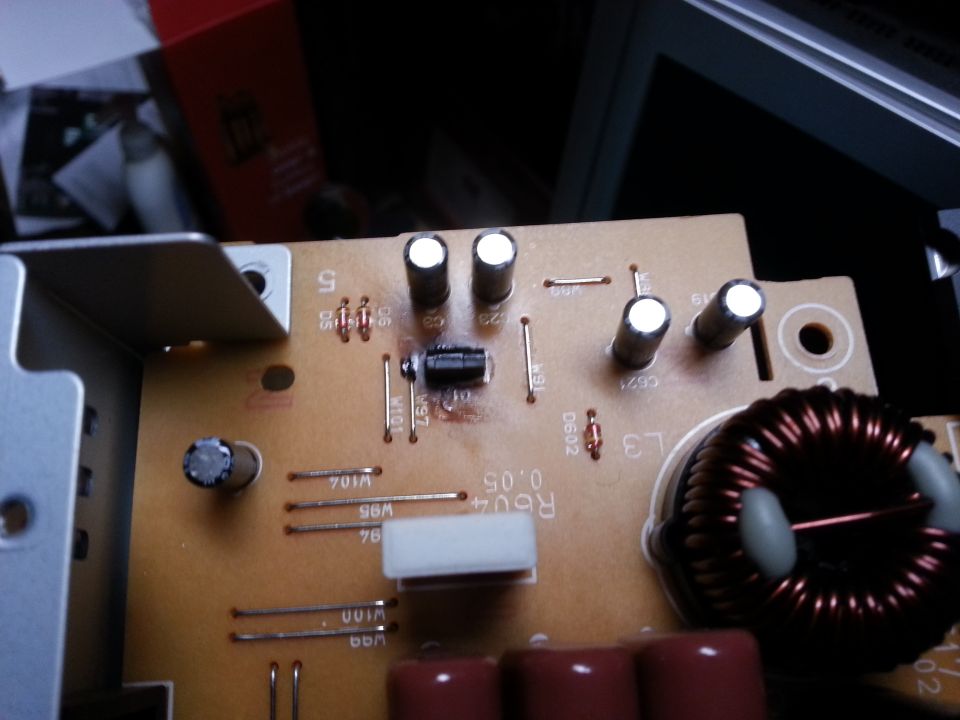 Close-up of a circuit board showing capacitors, resistors, and a toroidal inductor. Text 'R604 0.05' is visible