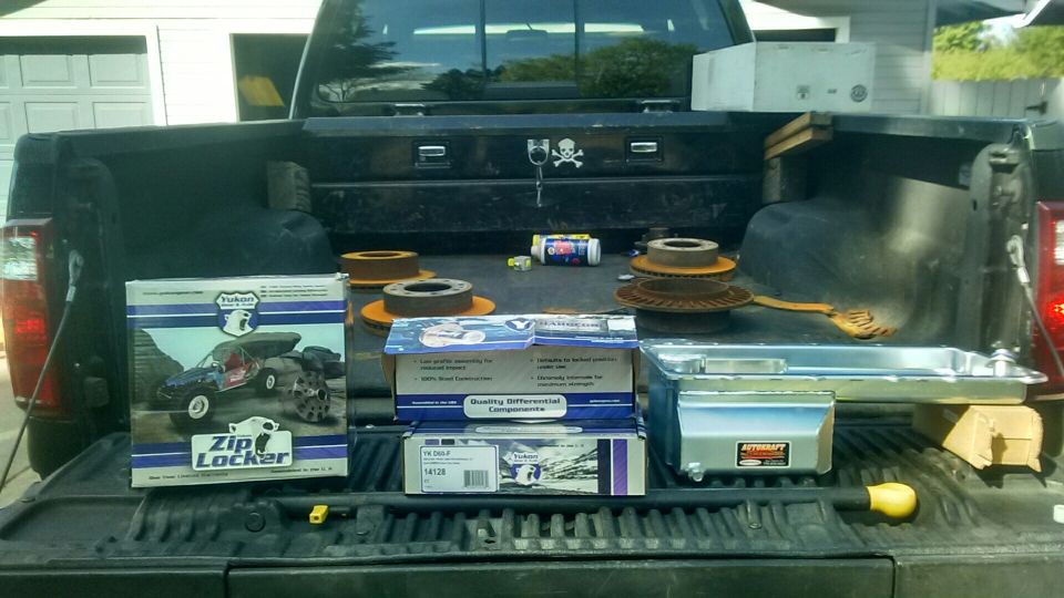 Pickup truck bed loaded with brake rotors, differential components, and a zip locker box