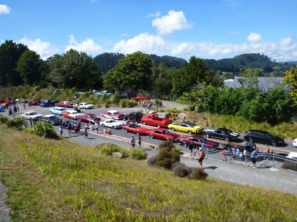 Outdoor car show with dozens of classic cars parked in rows under a blue sky with clouds
