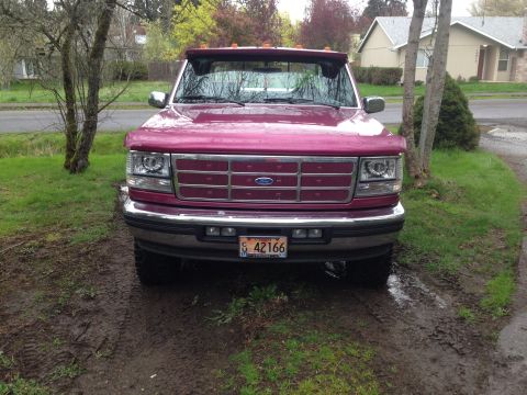 1992 Ford F-150 - This 1992 Ford F-150 truck is shown from a direct front-facing angle, parked on a dirt and grass area.
