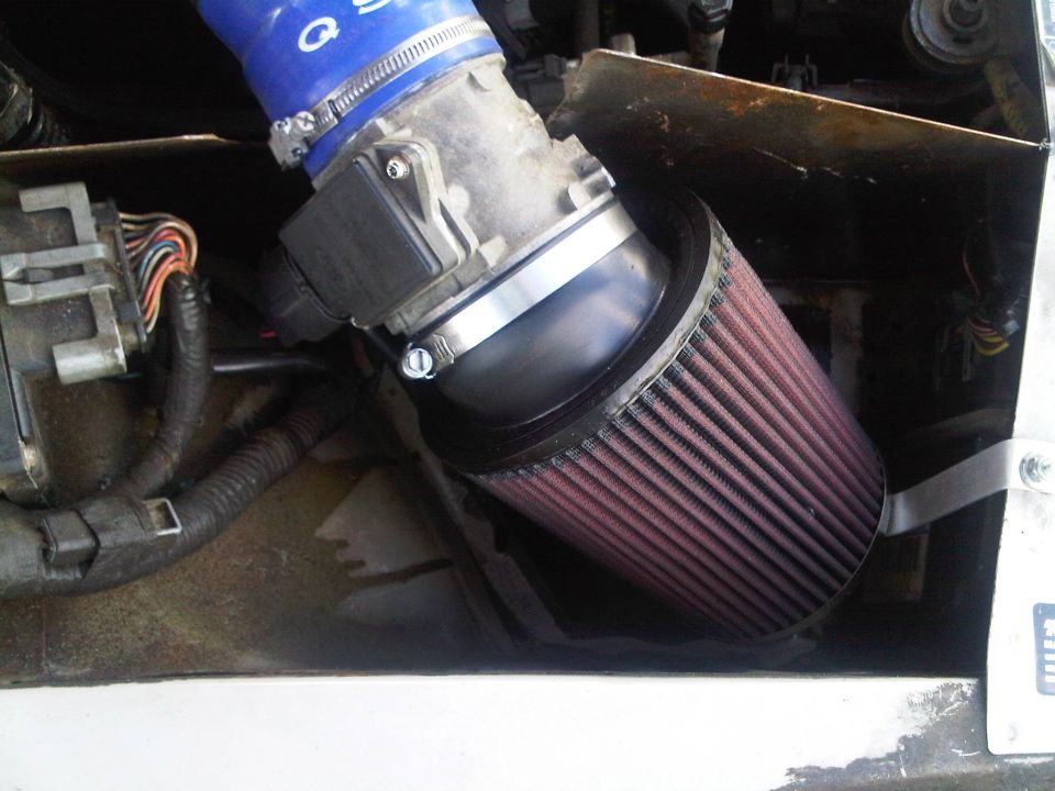 Engine air intake assembly with blue hose and red cone filter, attached to a black sensor