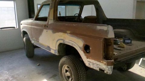 1982 Ford Bronco - This Ford Bronco is undergoing body work, with primer and filler visible on its exterior panels.