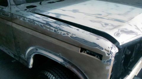 1982 Ford Bronco - This 1982 Ford Bronco is shown with its front fender and hood covered in body filler, indicating it is undergoing repairs or customization.