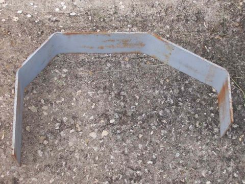 1982 Ford F-100 - A gray metal bracket with visible rust is pictured on a gravel surface.