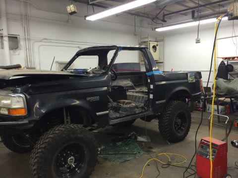 1992 Ford Bronco - A Ford Bronco is being worked on in a garage, with its roof and interior partially disassembled.