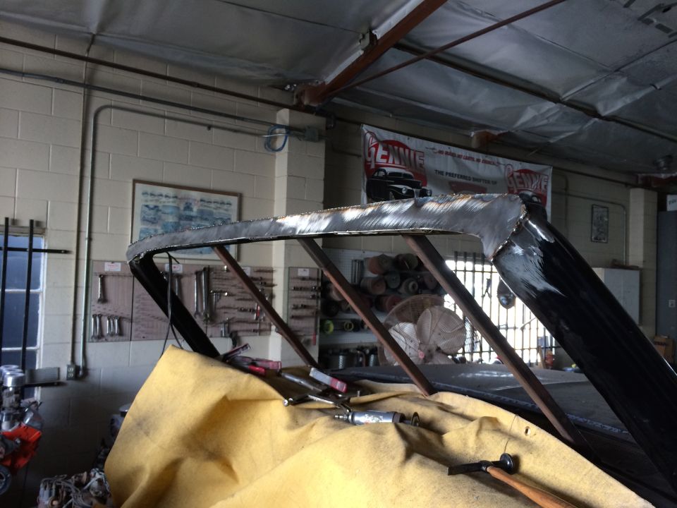 Vehicle roof structure undergoing modification, showing cut metal and support beams