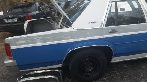 1991 Ford LTD Crown Victoria - Rear view of a two-tone blue and white 1991 Ford Crown Victoria LTD with its trunk open, parked beside another Crown Victoria.