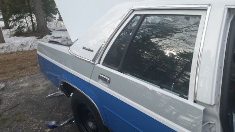 1991 Ford LTD Crown Victoria - The rear passenger side of a two-tone Ford Crown Victoria is shown with the hood open.