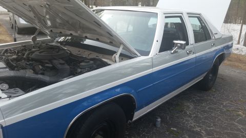 1991 Ford LTD Crown Victoria - This two-tone blue and silver sedan has its hood open, revealing the engine compartment.