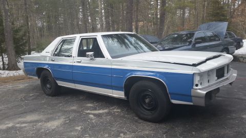 1991 Ford LTD Crown Victoria - A two-tone blue and white 1991 Ford Crown Victoria sits in a driveway with its hood ajar and front grille missing.