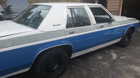 1991 Ford LTD Crown Victoria - A two-tone Ford Crown Victoria is parked outdoors next to another vehicle.