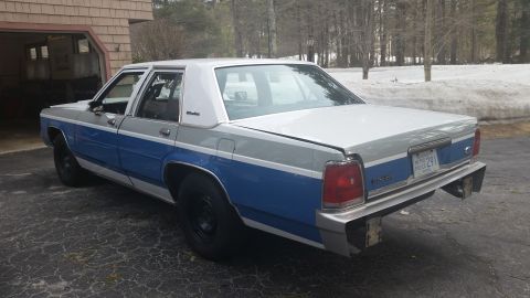 1991 Ford LTD Crown Victoria - Rear three-quarter view of a two-tone blue and silver sedan parked on a driveway.