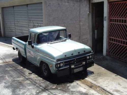 1970 Ford F-100 - Light blue 1967 Ford F-100 pickup truck parked in front of a building with a metal gate.
