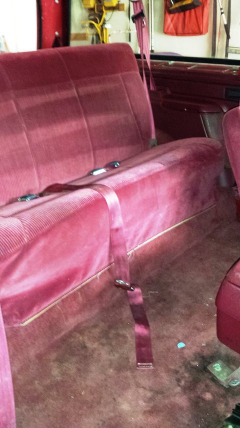 2001 Ford F-150 - The interior of a vehicle shows a red velour bench seat with seatbelts.