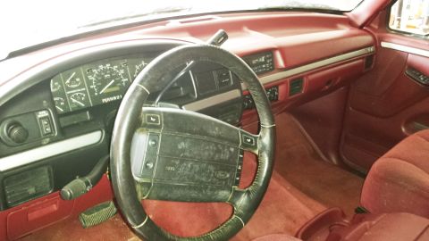 2001 Ford F-150 - The interior of a 1994 Ford Bronco features red carpeting and upholstery, a black steering wheel, and a dashboard with gauges.