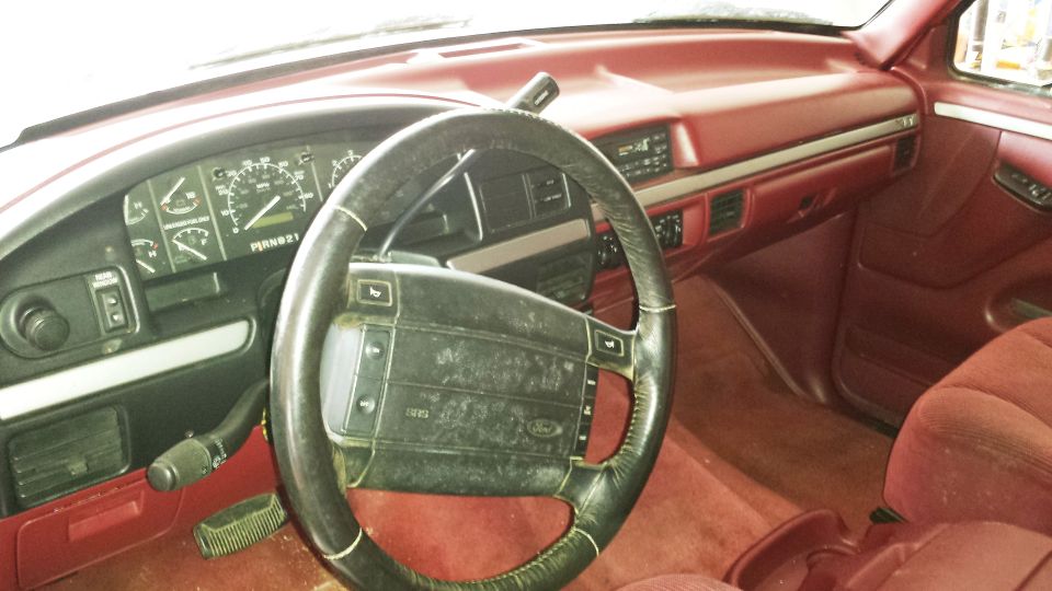 Interior view of a 1994 Ford Bronco with red upholstery and a black steering wheel