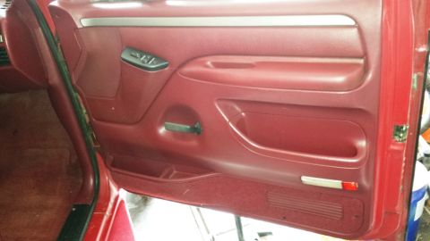 2001 Ford F-150 - Interior view of a red door panel with a silver trim strip above the window controls.