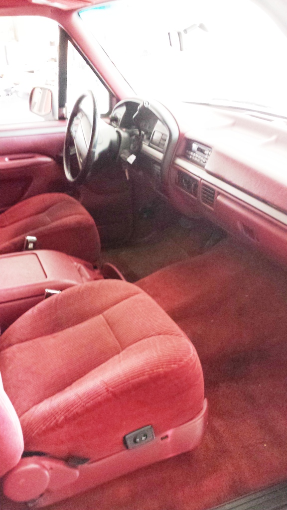 Interior view of a red truck cab, showing seats, dashboard, and steering wheel