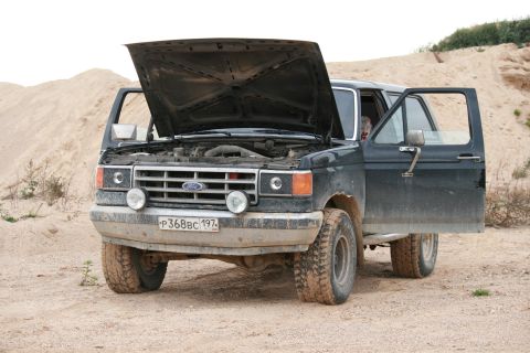 1987 Ford Bronco - This 1987 Ford Bronco is parked in a sandy area with its hood and driver's door open.