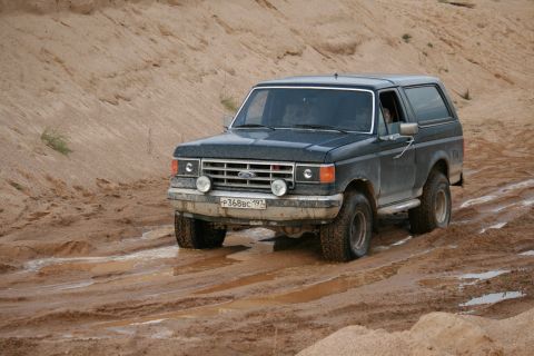 1987 Ford Bronco - Ford Bronco navigates a challenging muddy terrain.