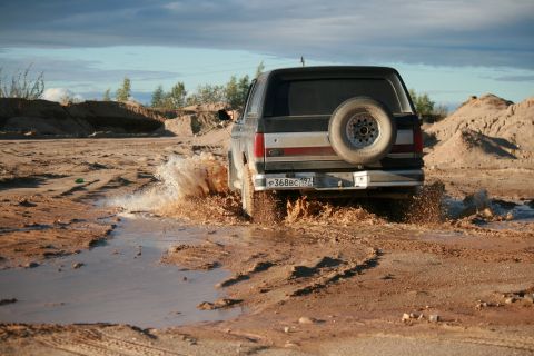 1987 Ford Bronco - A 1987 Ford Bronco splashes through a muddy terrain, kicking up water and dirt.