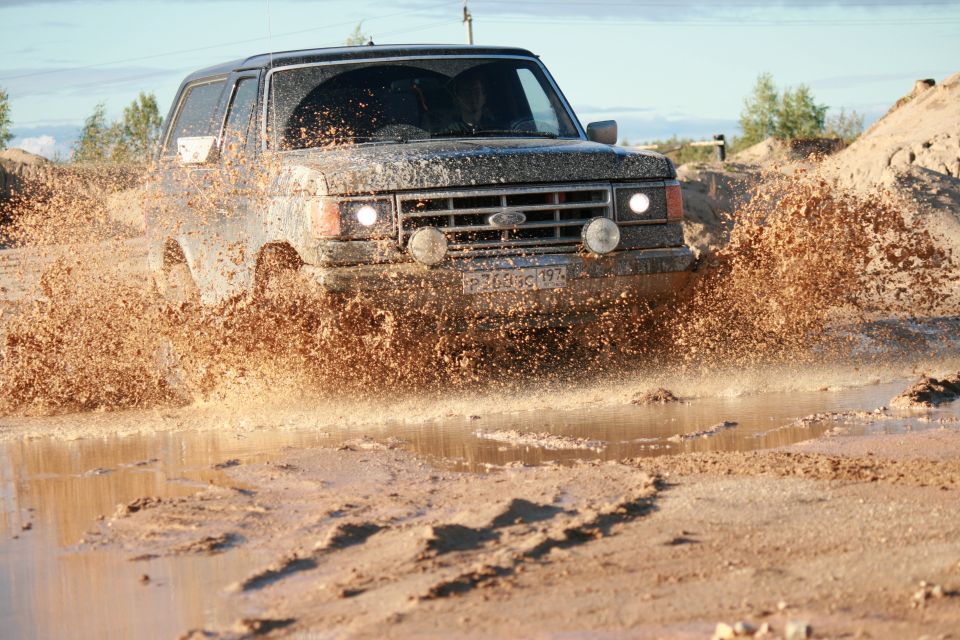 1987 Ford Bronco driving through mud, front view
