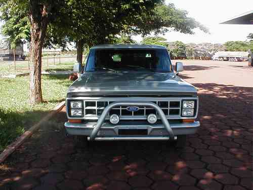 Front view of a light gray Ford truck with chrome bull bar and driving lights on red paver lot