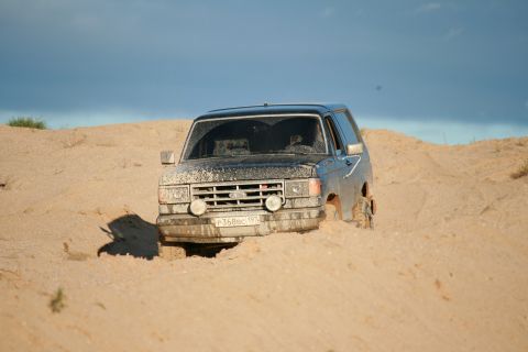 1987 Ford Bronco - This 1987 Ford Bronco is stuck in the sand, showing its front grille and headlights.