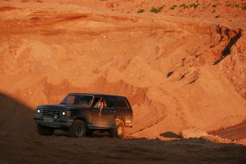1987 Ford Bronco - Ford Bronco navigates a sandy terrain under warm lighting.