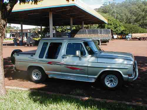Silver 1970 Ford F-100 pickup truck with custom decals parked under a canopy