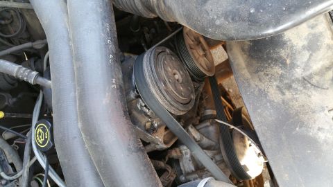 1990 Ford Bronco - Close-up view of the engine bay, focusing on the AC compressor and drive belts. The Supermotors.net logo is present in the lower right corn…