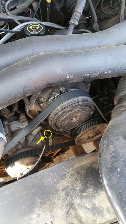 1990 Ford Bronco - Close-up view of the engine bay, highlighting the belt-driven components and a specific bolt indicated by an arrow.