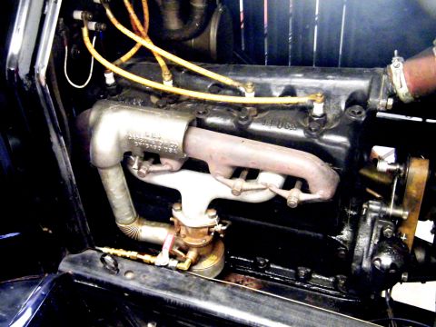 1915 Ford Model T - Close-up view of the engine compartment of a 1915 Ford Model T, highlighting the exhaust manifold and spark plug wiring.