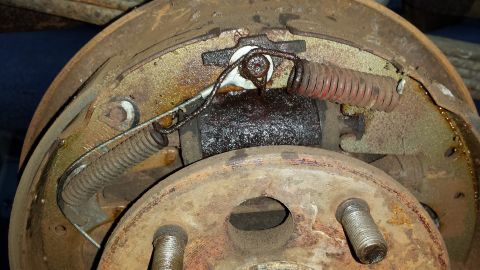 1978 Ford Bronco - Close-up view of a rusty drum brake assembly, showing worn springs and grease buildup.