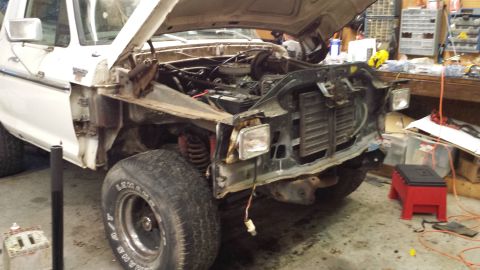 1978 Ford Bronco - Front end of a 1978 Ford Bronco disassembled for repair, showing the engine bay and grille area.