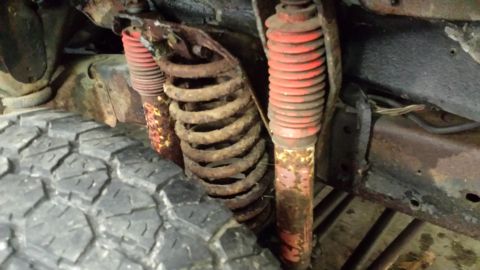 1978 Ford Bronco - The vehicle's suspension system shows significant rust and wear on its springs and shock absorbers.
