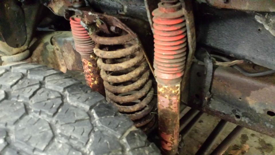 close-up of rusty suspension springs and red shocks on a vehicle frame